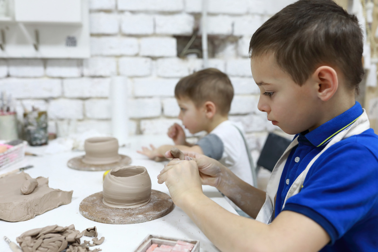 Children sculpt clay mugs